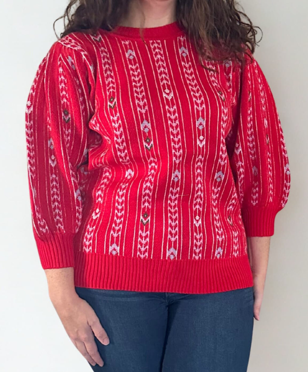Person wearing a red sweater with white pattern against a plain background