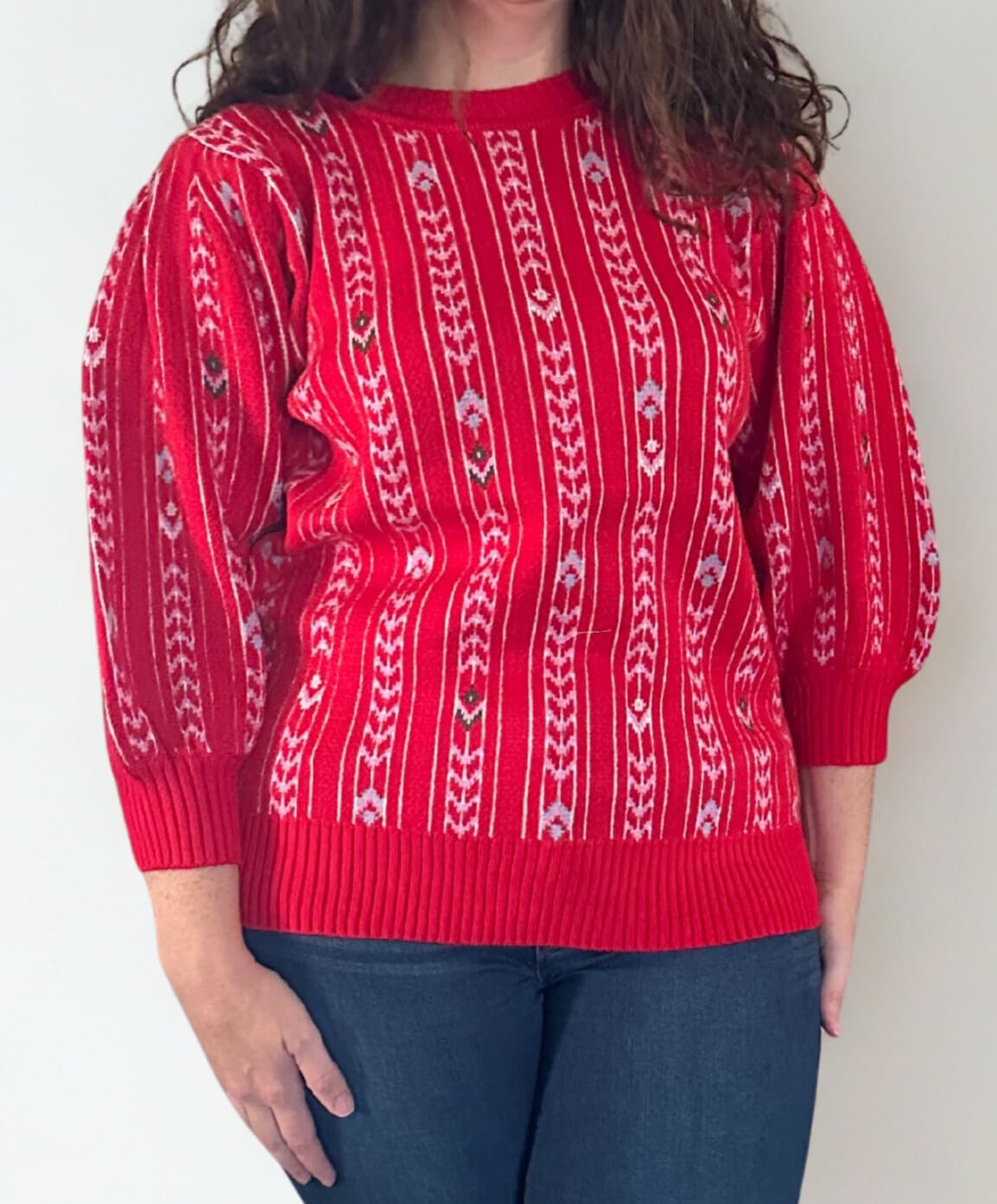 Person wearing a red sweater with white pattern against a plain background