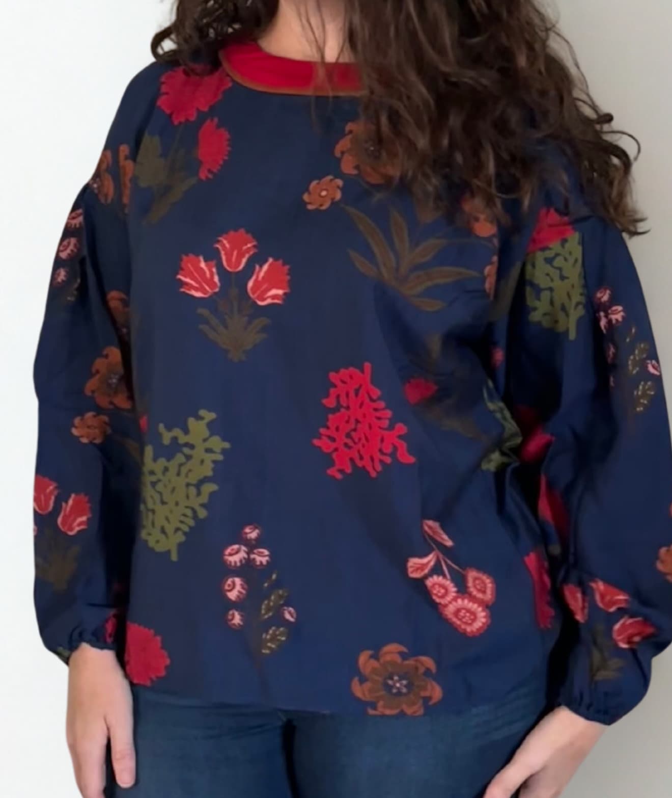 Navy blue sweater with red floral patterns worn by a person