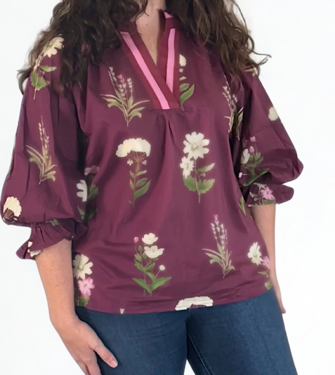 Woman wearing a purple floral blouse with blue jeans on a white background