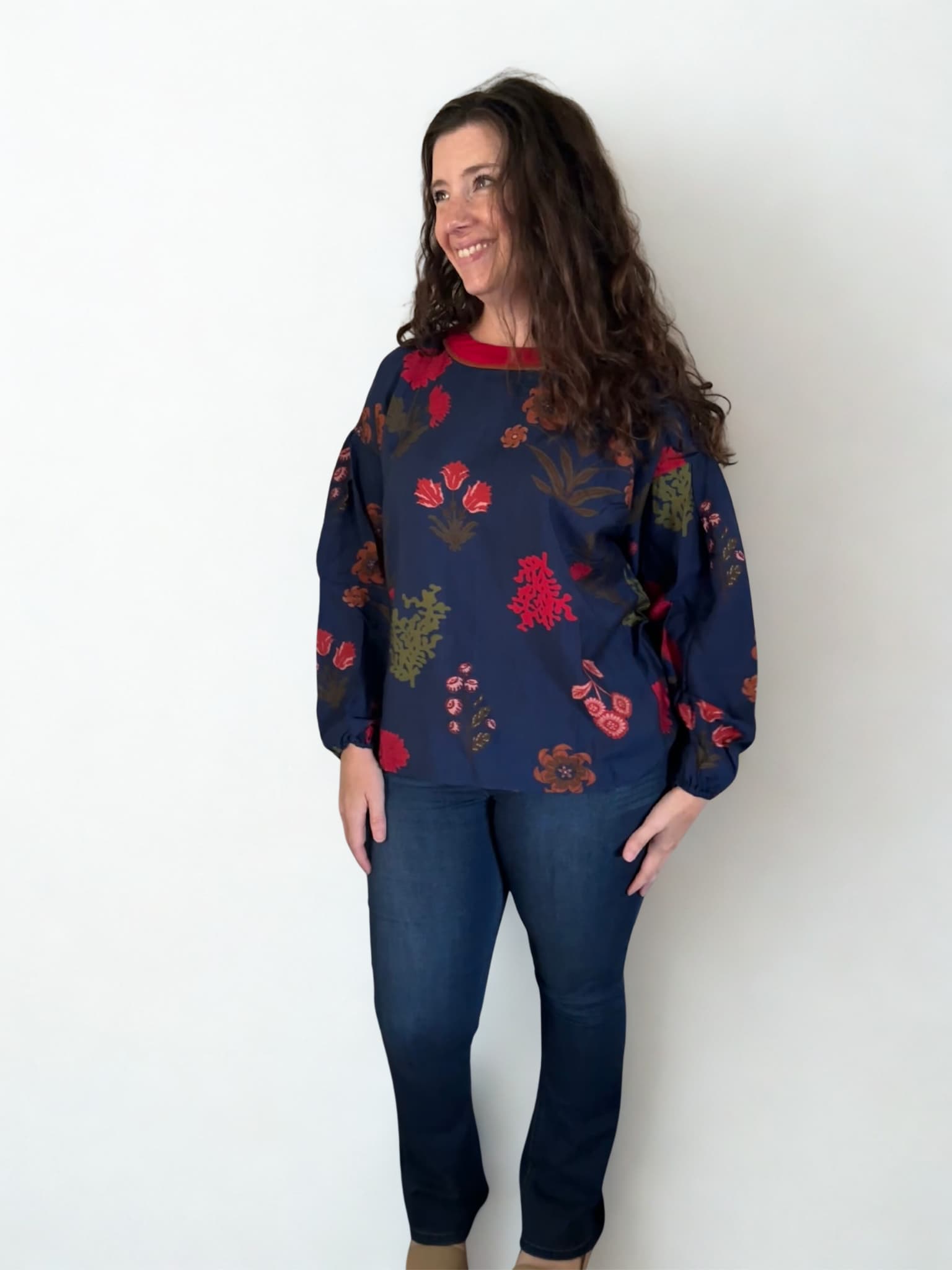 Woman wearing a navy sweater with colorful floral patterns against a white background