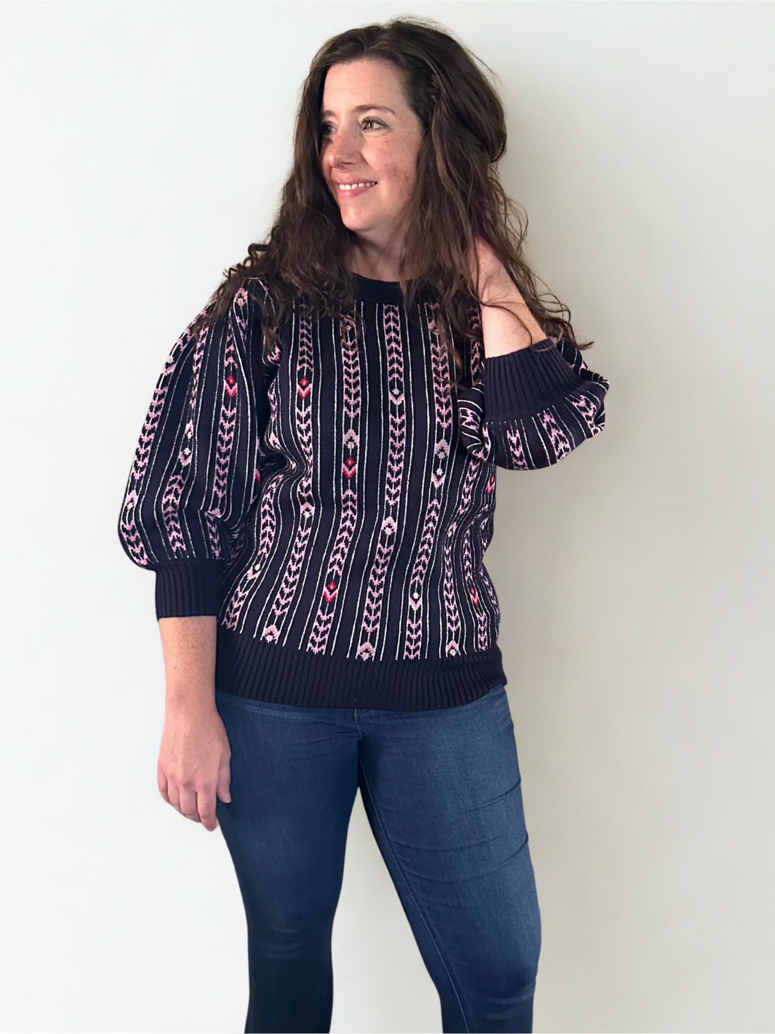 Woman wearing a patterned navy sweater against a white background