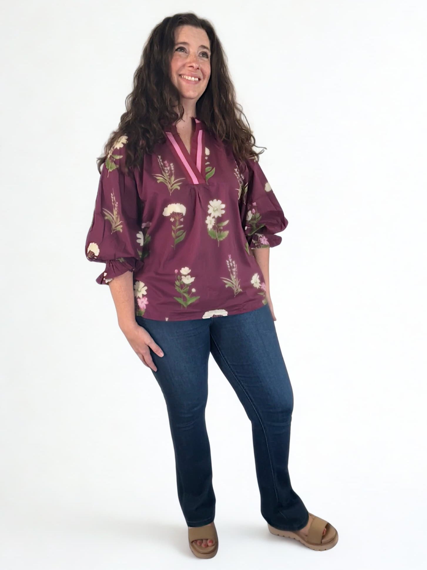 Woman wearing a floral blouse and jeans on a white background