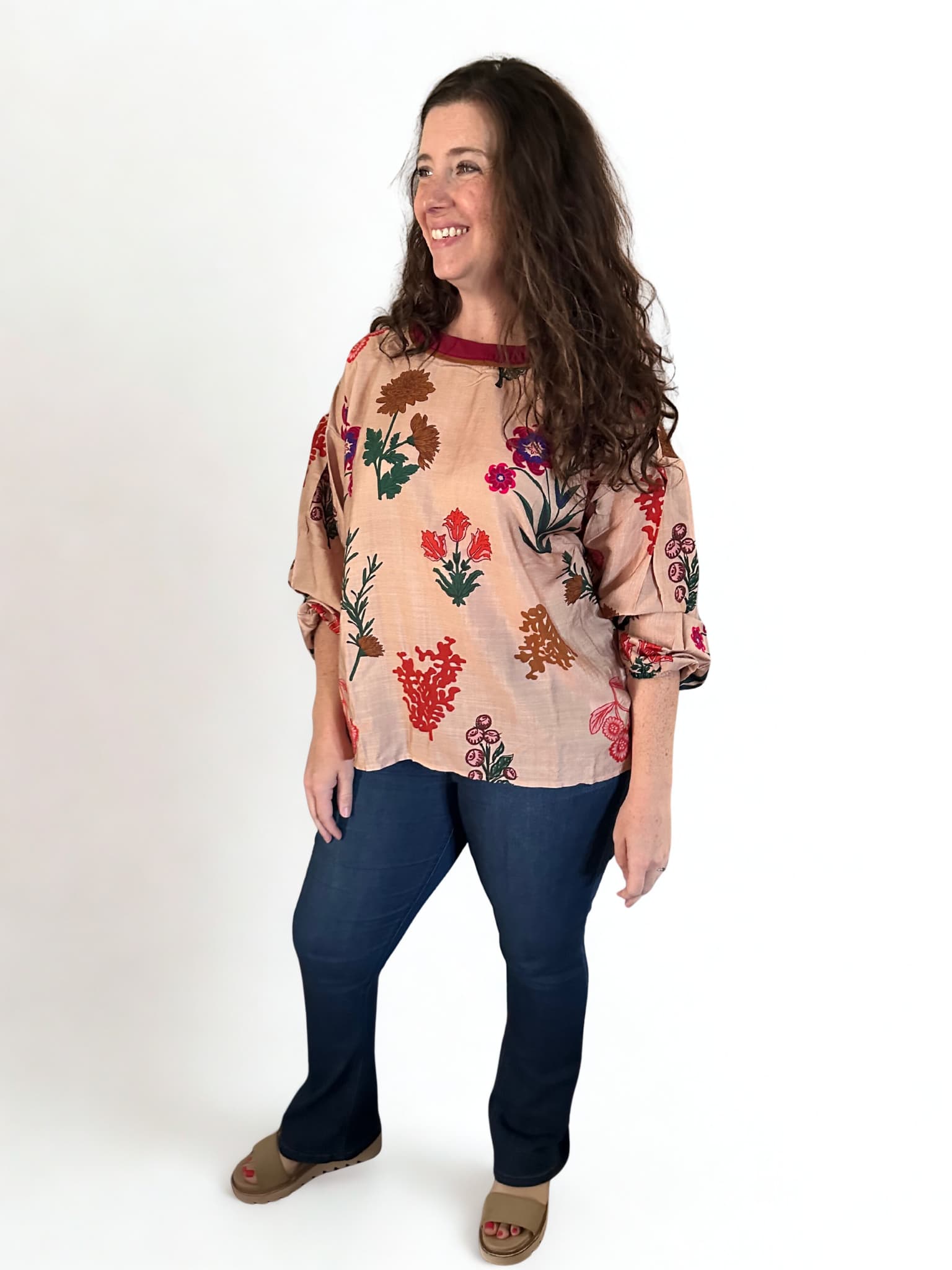 Woman wearing a floral blouse and blue jeans on a white background