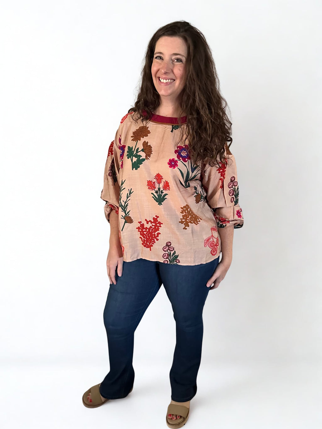 Woman wearing a floral blouse and blue jeans on a white background