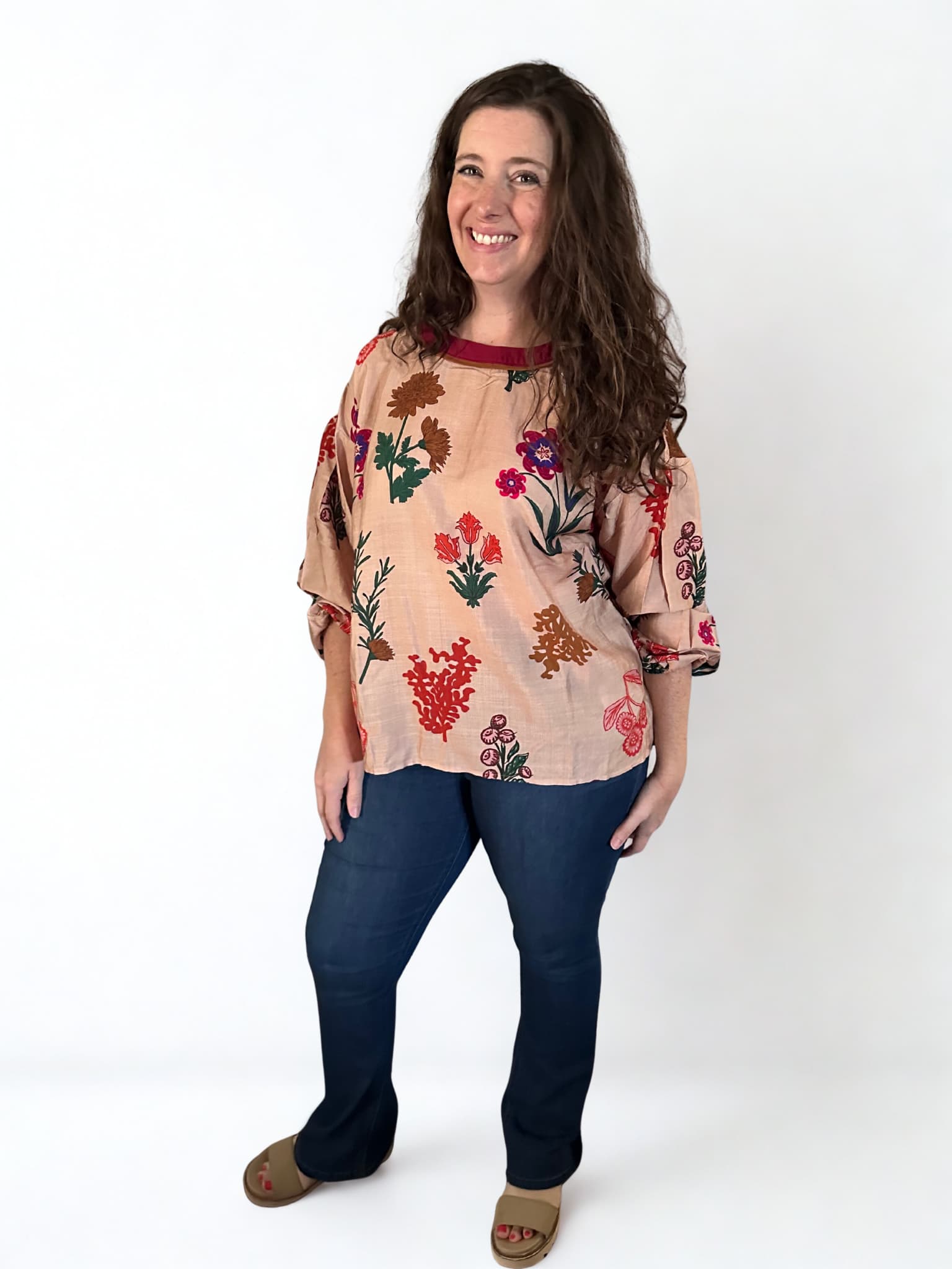 Woman wearing a floral blouse and blue jeans on a white background
