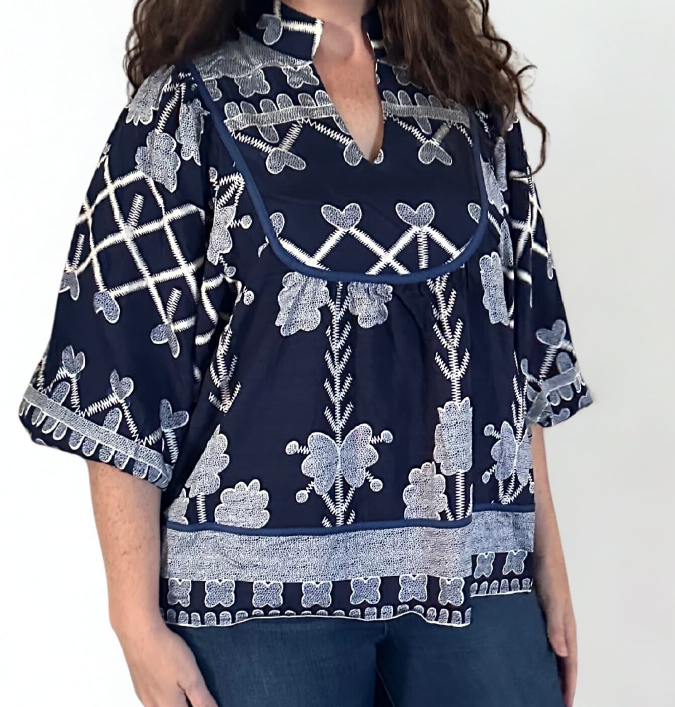 Navy blue blouse with white embroidery on a plain background