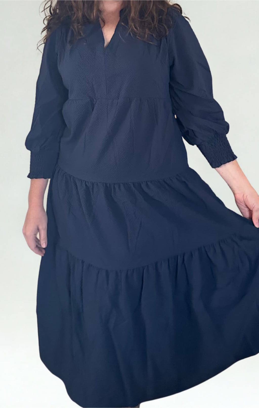 Person wearing a navy blue dress with long sleeves on a white background