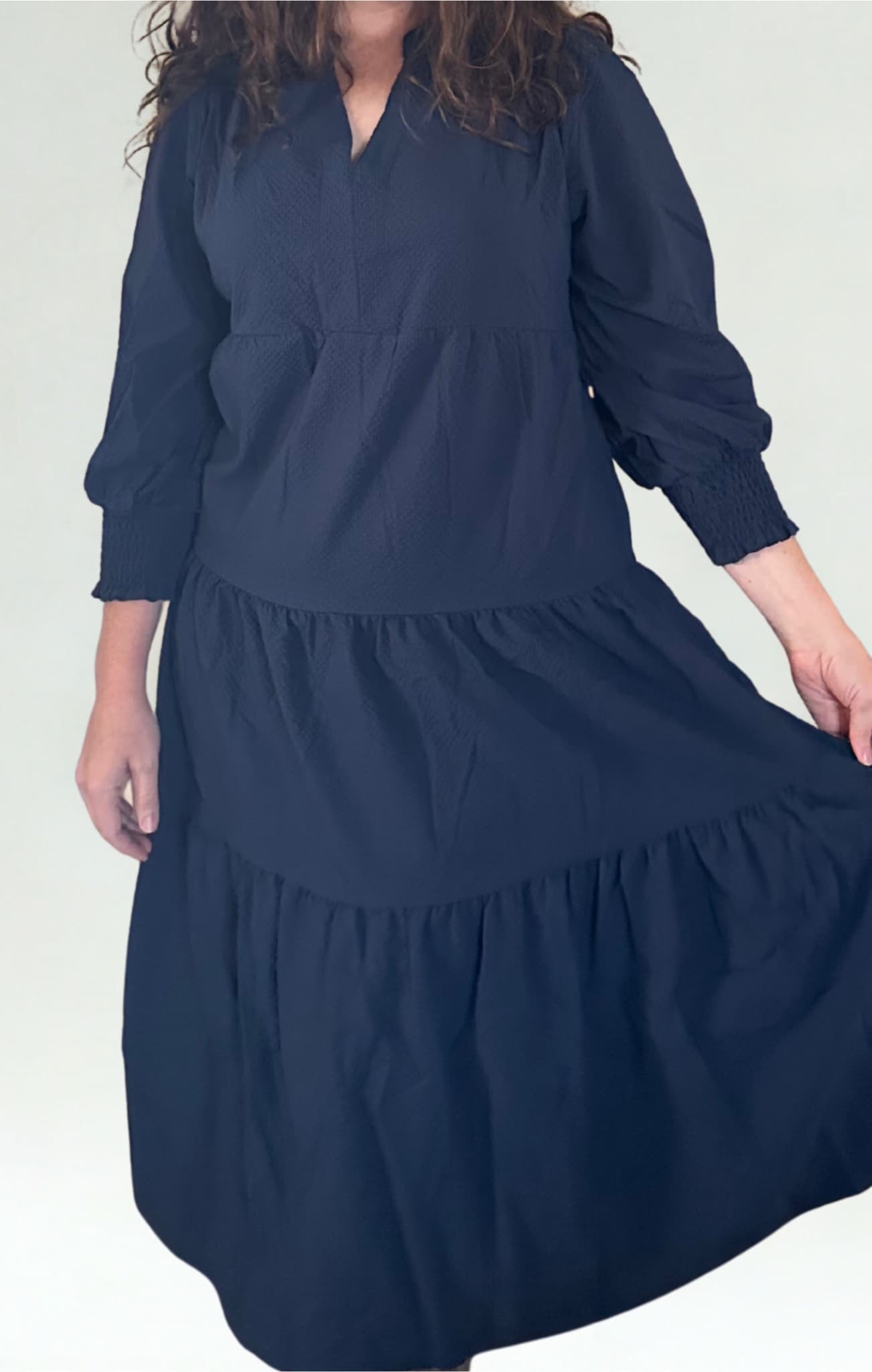 Person wearing a navy blue dress with long sleeves on a white background