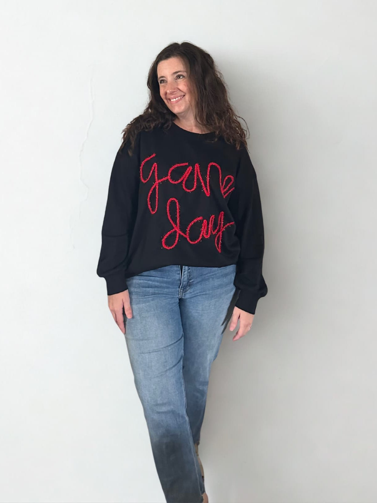 Woman wearing black sweatshirt with front tuck with red lettering saying game day